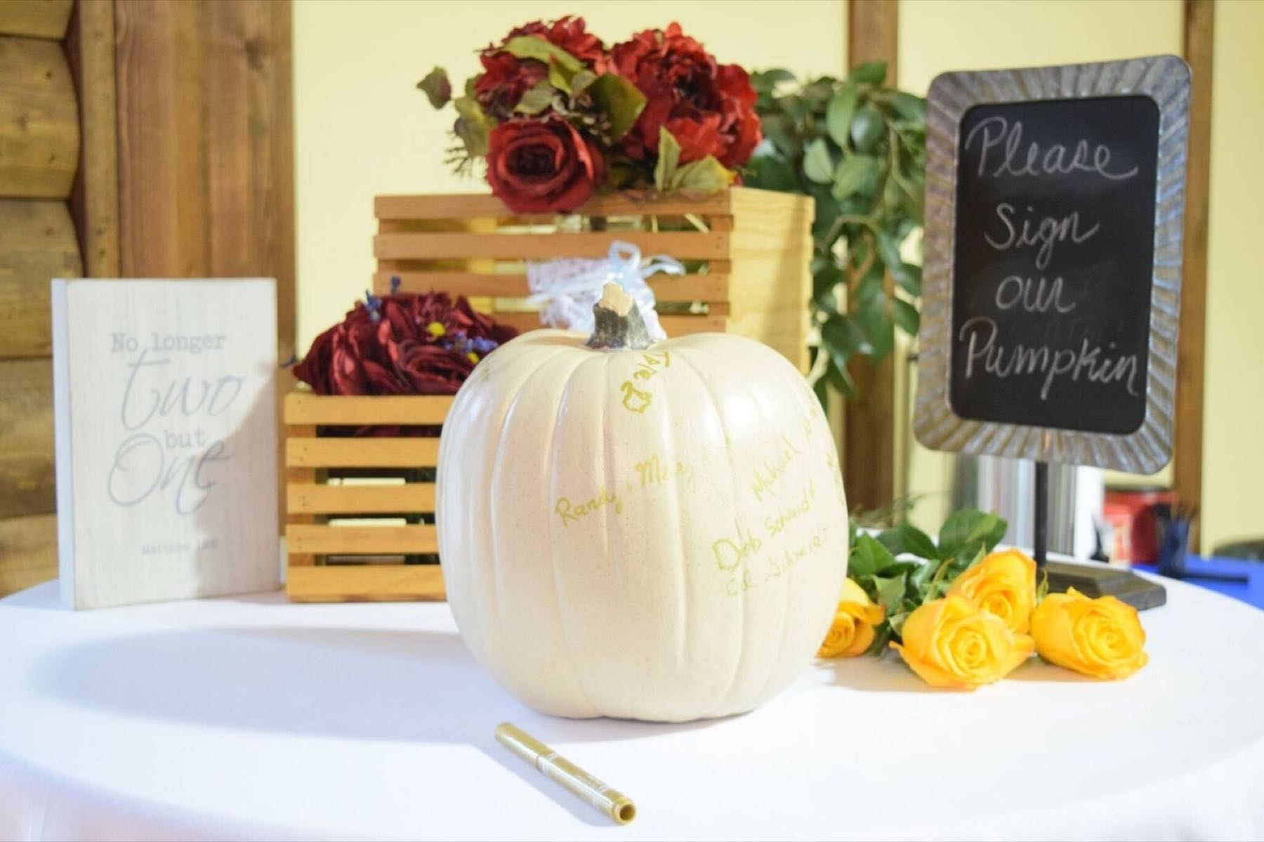 Guest-book table with a signed pumpkin and autumn flowers