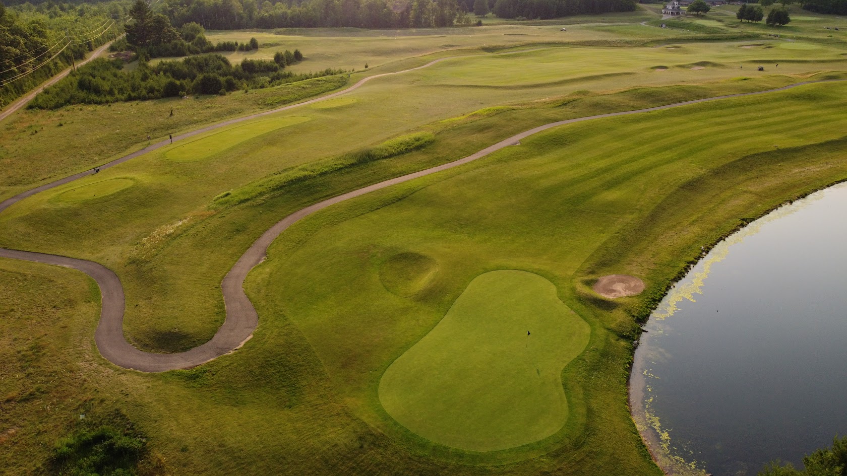 Green beside a pond with a winding cart path
